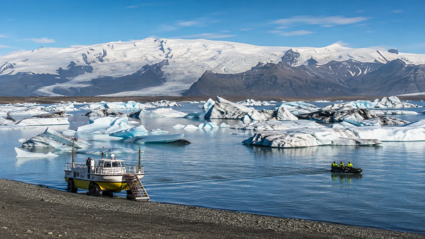 An amphibian boat and a small Zodiac among icebergs on the lagoon