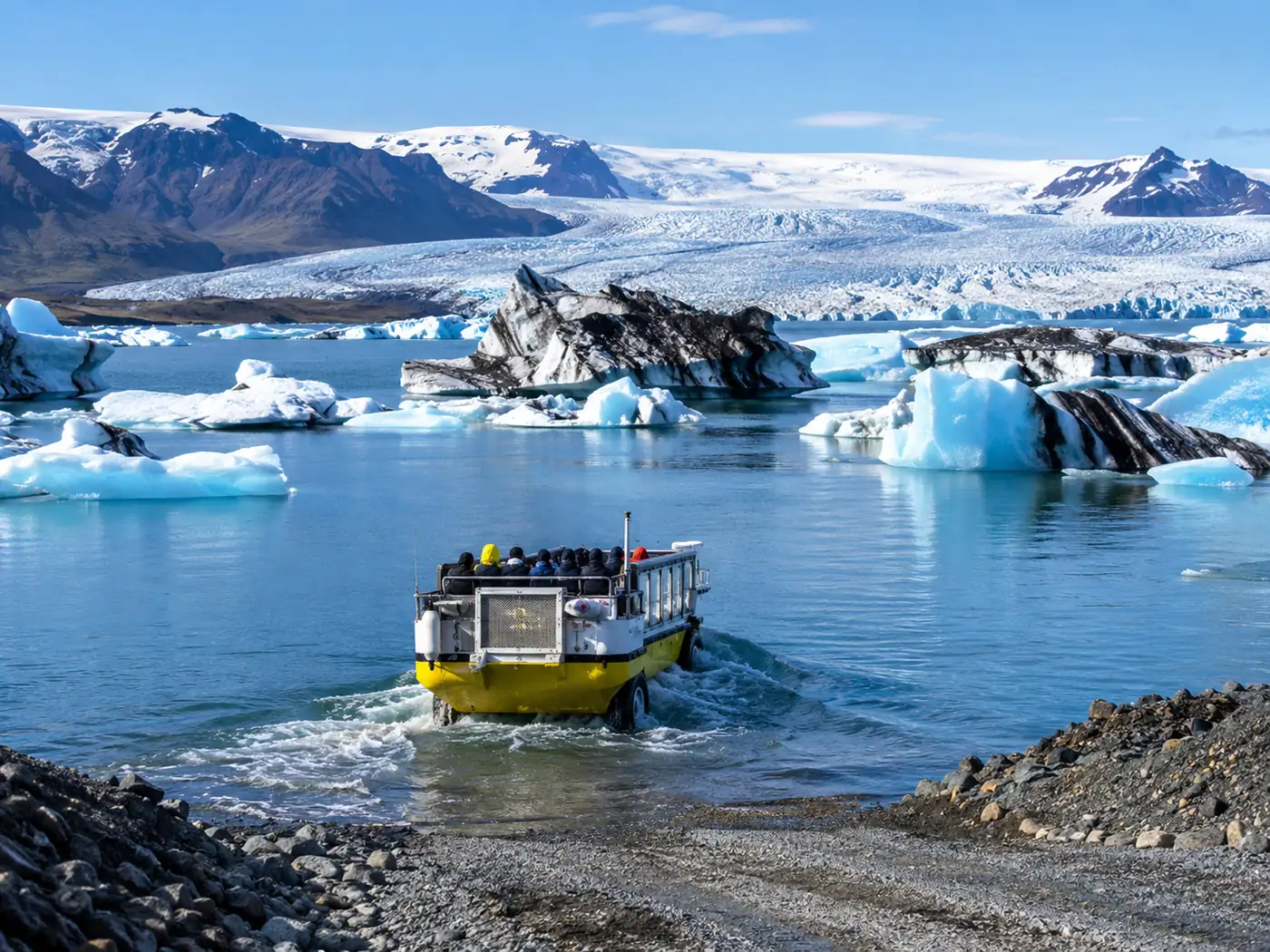 An amphibian boat driving down a gravel ramp into the lagoon